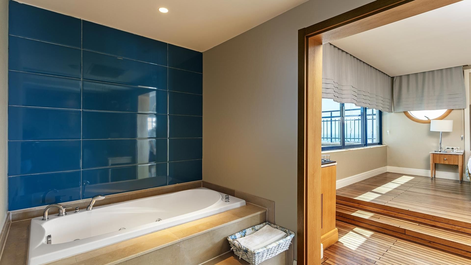 Ванная комната в Titanic Deluxe Lara – Admiral Suite с синими кафельными стенами, деревянным полом и ванной.