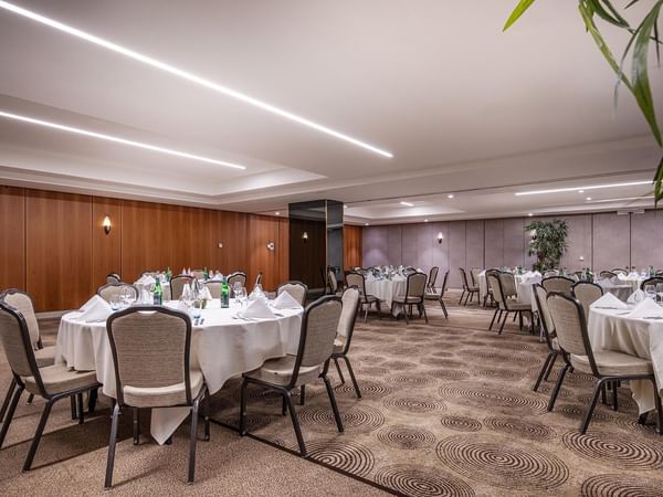 Circular carpet with round-shaped tables and chairs in an event room at Warwick Grand-Place Brussels.