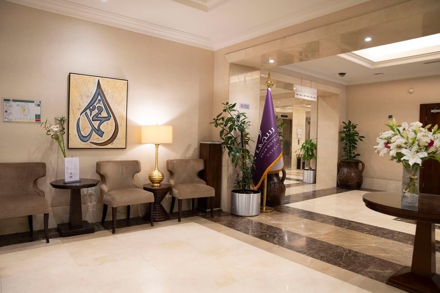 Lobby featuring Arabic calligraphy art with plush seating and a Saja Hotels flag at Saja by Warwick Makkah
