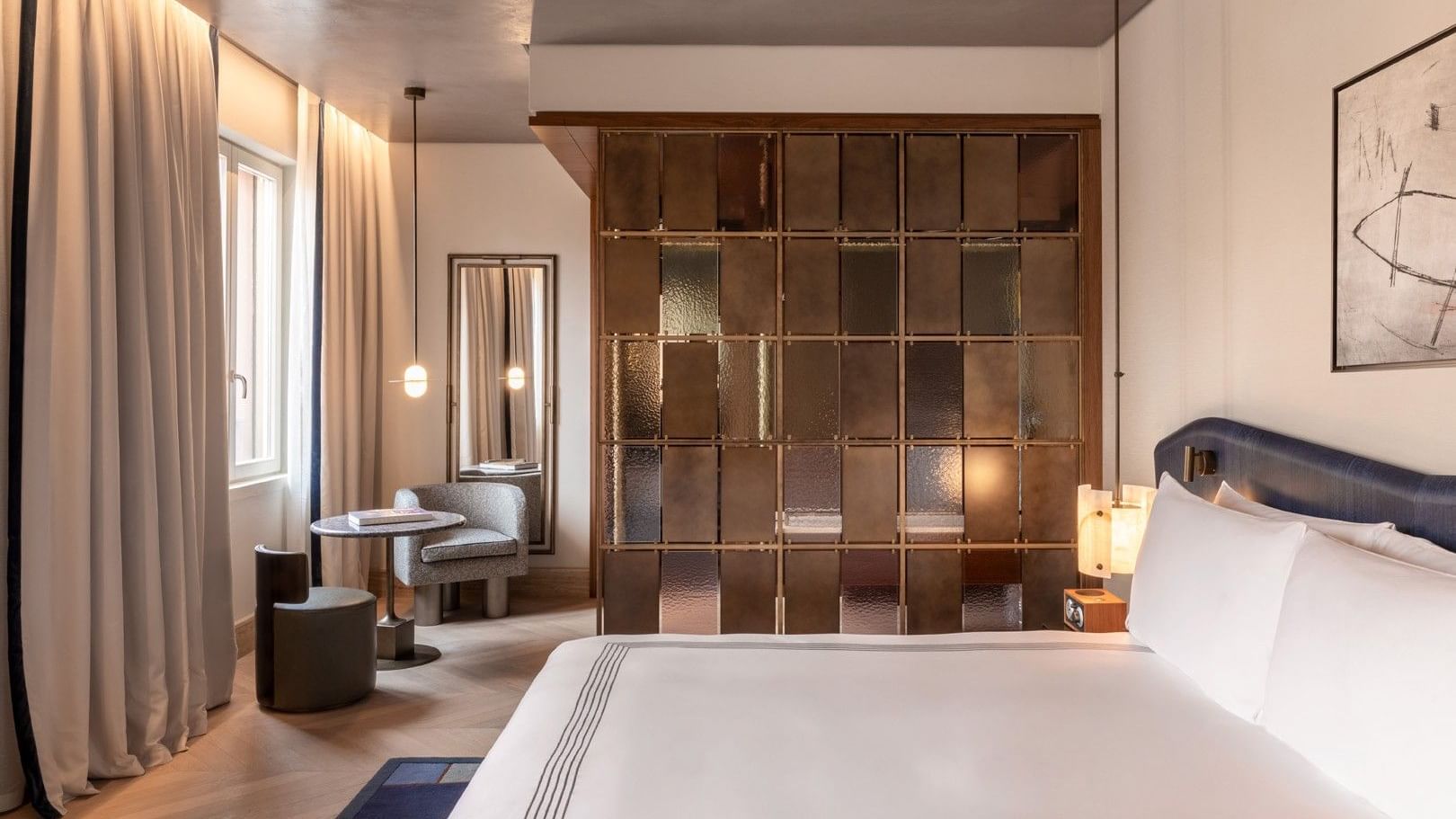 Deluxe king bed room with bronze glass partition, seating area, and modern decor at The Thompson Rome, Roma