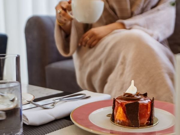 Glazed chocolate dessert on a pink plate by a guest in 24/7 In-Room Dining at Cantonal Hotel by Warwick Riyadh