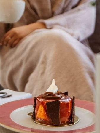 Glazed chocolate dessert on a pink plate by a guest in 24/7 In-Room Dining at Cantonal Hotel by Warwick Riyadh