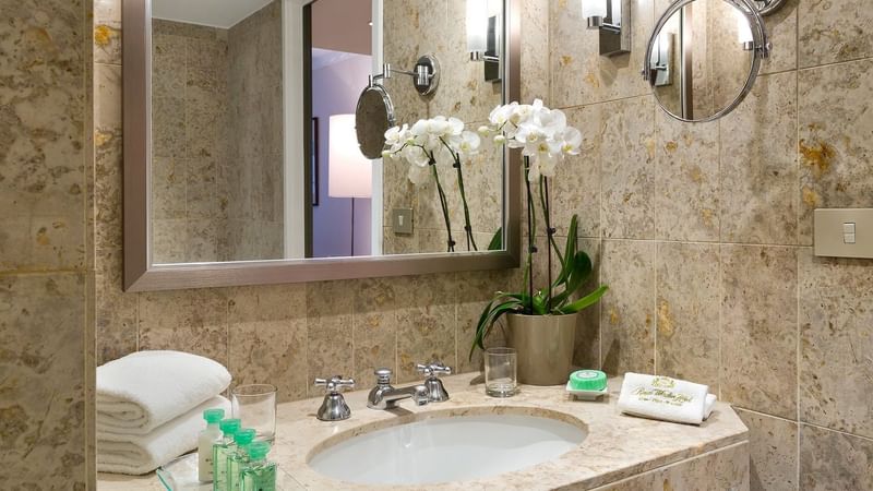 Bathroom vanity area with various toiletries in Premium Room at Brussels Warwick Hotels