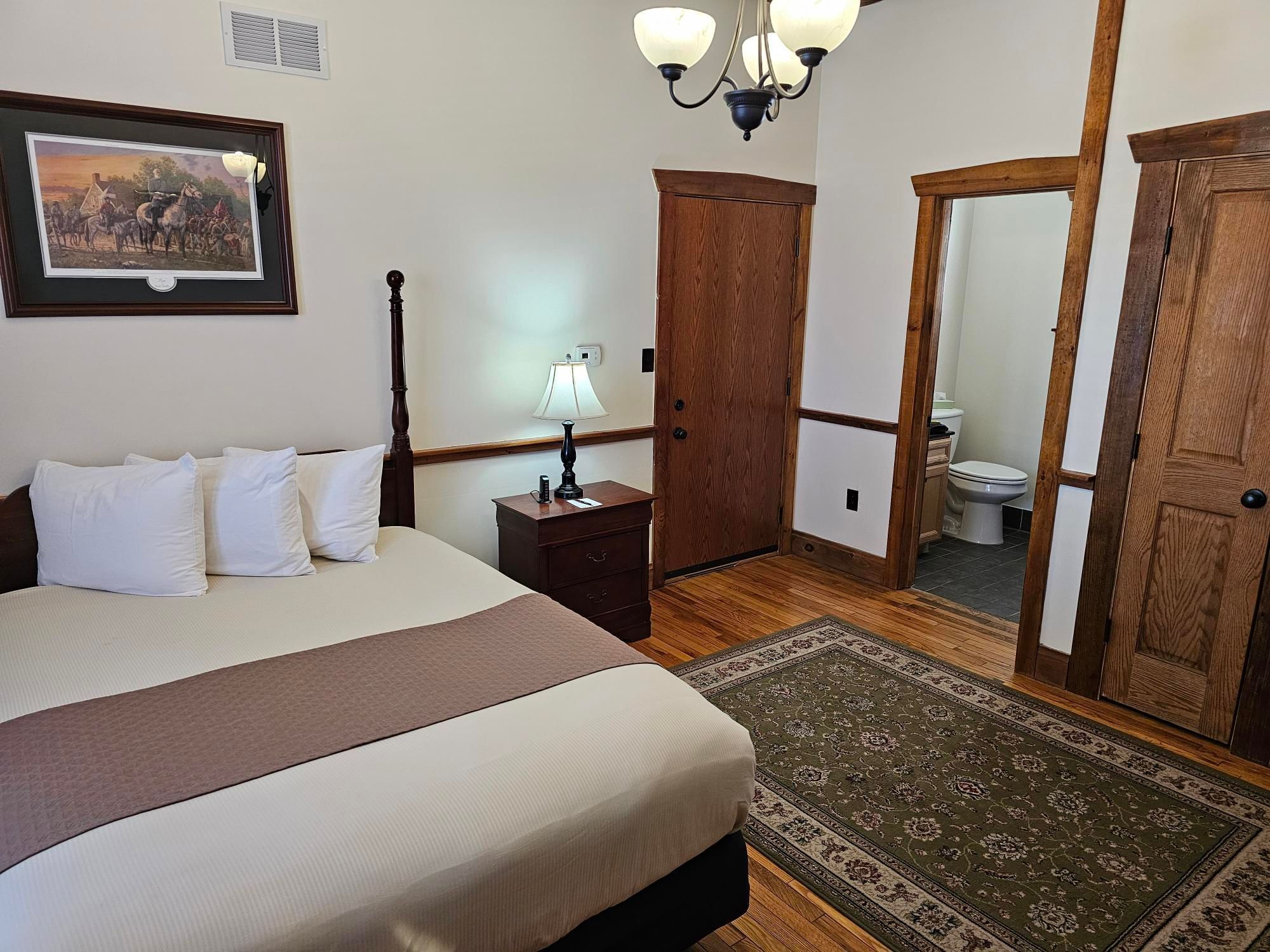 Corporal's Quarters bedroom with a queen bed, and a bathroom at The Lodges at Gettysburg hotel in PA.
