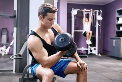A guy carrying a dumbbell in the Gymnasium