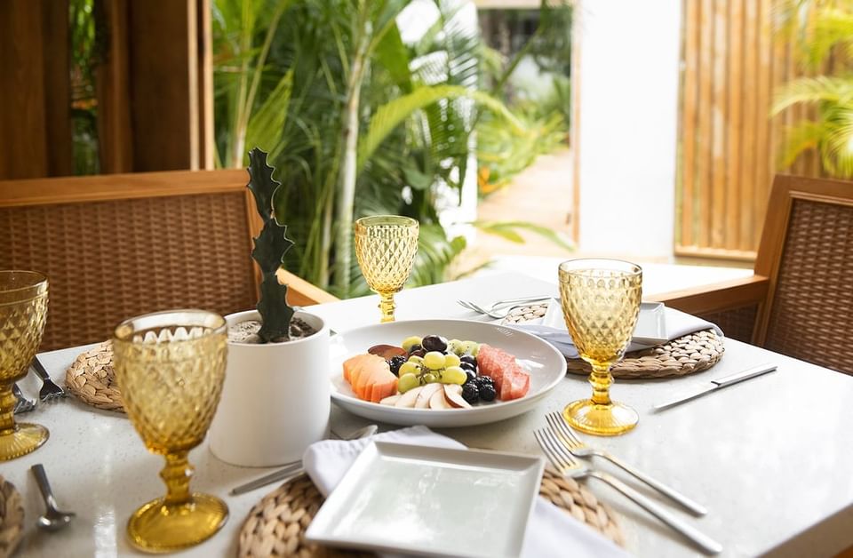 A luxurious breakfast setting with a fresh fruit plate, amber glasses, and a cactus centerpiece at the Ibagari Hotel