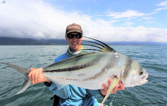 Angler holding a large silver roosterfish above ocean waters during a sportfishing trip near Jungle Vista Boutique Hotel