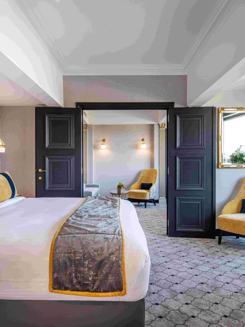 Luxe hotelkamer met kingsize bed, gouden fauteuils en elegante inrichting voor een romantisch verblijf