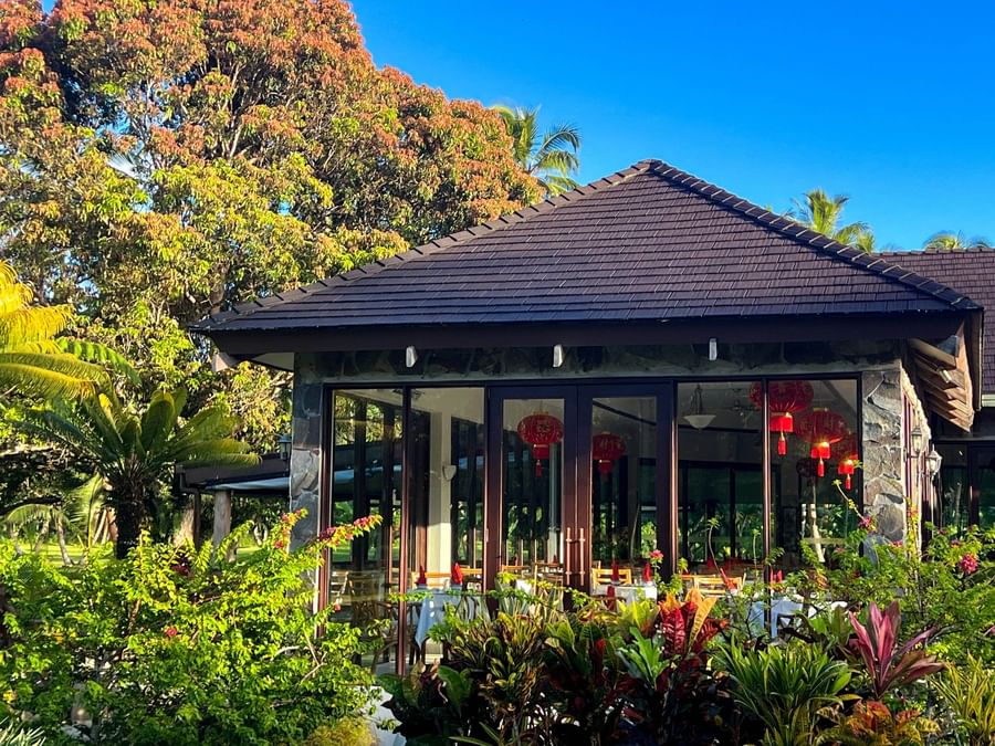 The Naviti Resort in Fiji with lush greenery, glass doors, and red lanterns.