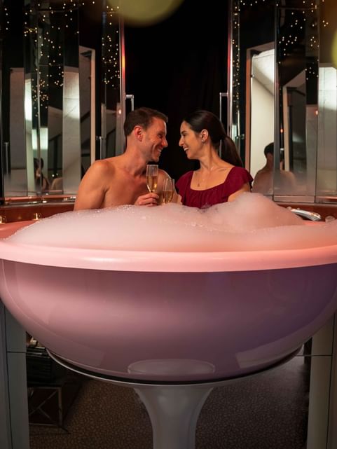 Couple having wine while relaxing in the Champagne Tower bathtub at Cove Pocono Resorts