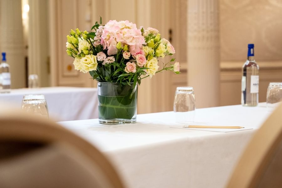 Bouquet de fleurs roses et blanches sur une table de réunion avec verres et bouteilles d'eau à Hotel Westminster Warwick Paris