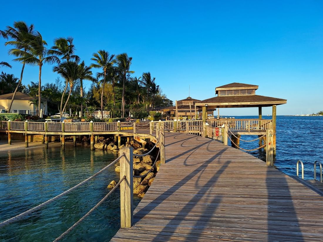 Wooden walkway by a shaded gazebo under a clear blue sky surrounding the water at Warwick Paradise Island Bahamas
