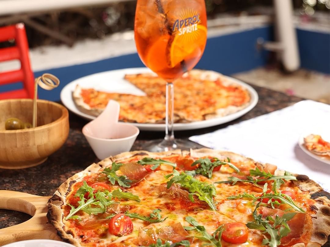 Pizza topped with arugula, tomatoes & Aperol Spritz served in Pizzaria Le Petit Cyrano at Billini Hotel Historic Luxury