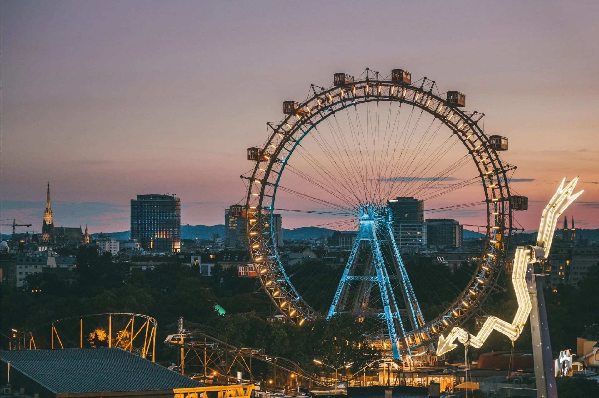 Wiener Riesenrad im Prater bei Abendstimmung mit beleuchteter Skyline und Blick über Wien