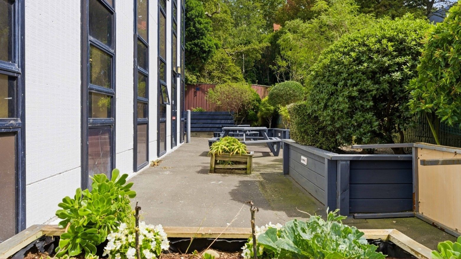 Side view of UniLodge Stafford House with garden beds and greenery.