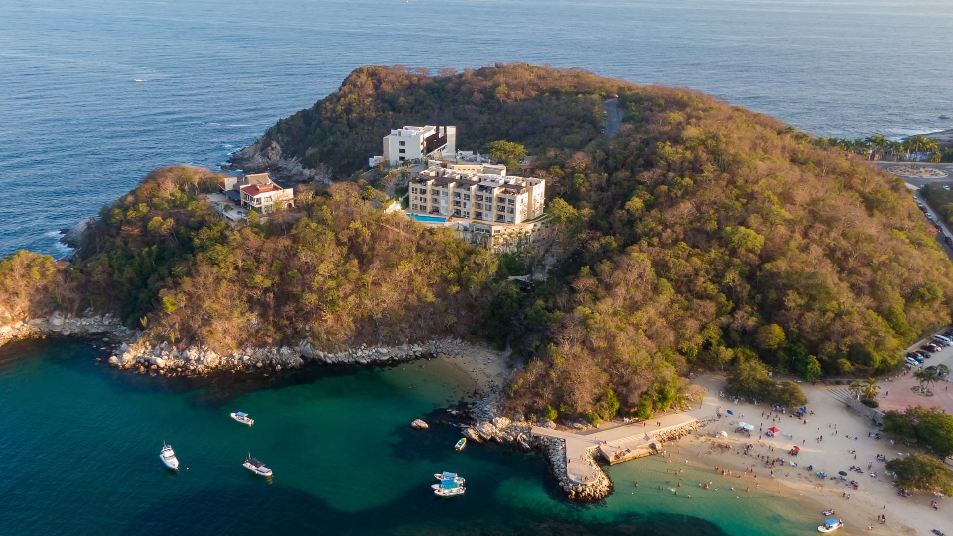 Aerial view of a lush hill, overlooking a small beach surrounded by the Huatulco Bays near Camino Real Zaashila Huatulco