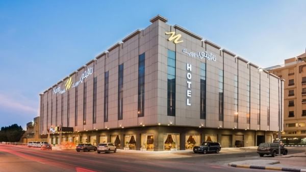 L'immeuble « Modern Naviti » de Warwick Al Khobar, avec son enseigne lumineuse et des voitures garées devant, au crépuscule