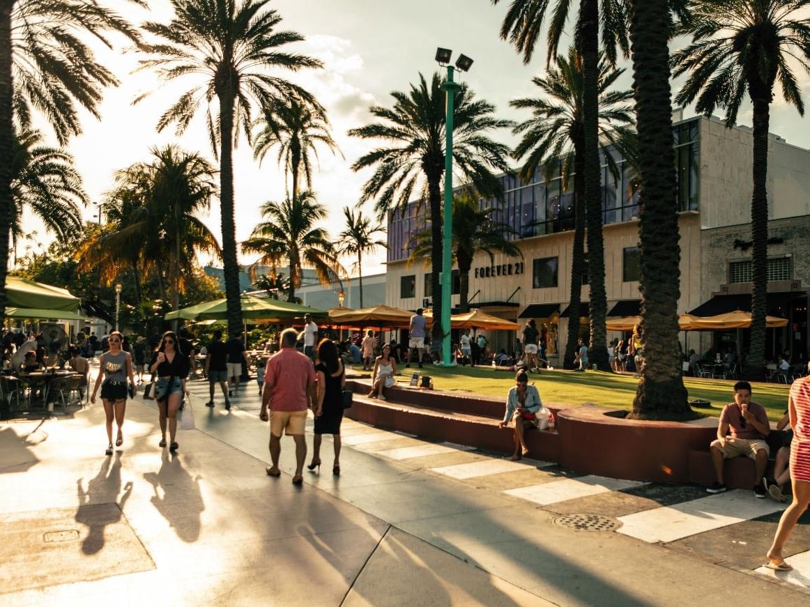 Sunny, palm-lined Lincoln Road Mall near Riviera Hotel South Beach with pedestrians and outdoor café seating