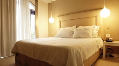 Habitación superior con balcón en las habitaciones del hotel Country International Barranquilla, con una cama grande y una iluminación cálida