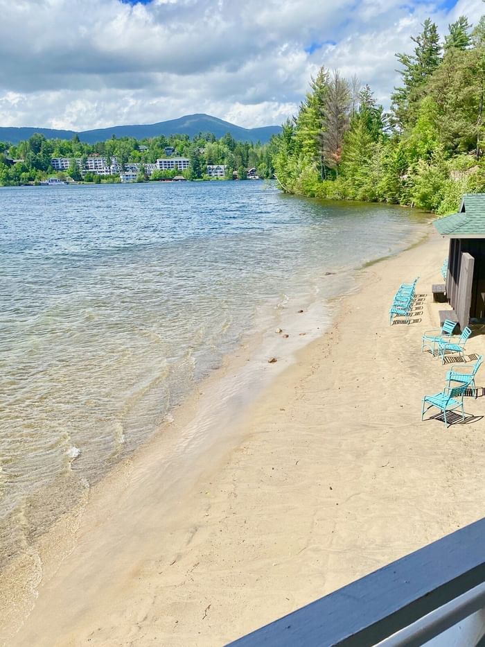 The sandy private beach area and lake at Lake Placid Club Grandview with turquoise chairs and boat houses