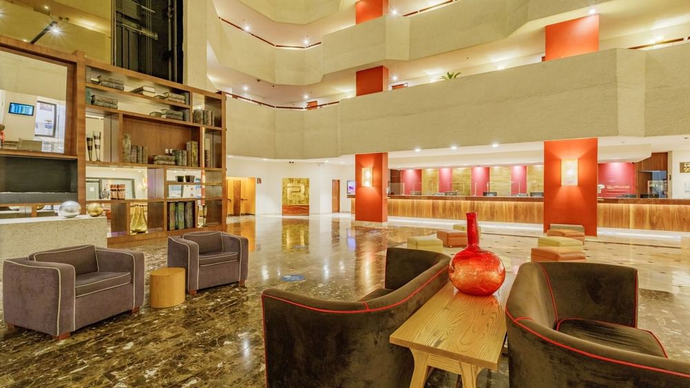 Plush armchairs by a wooden table in the atrium lobby at Camino Real Aeropuerto Mexico