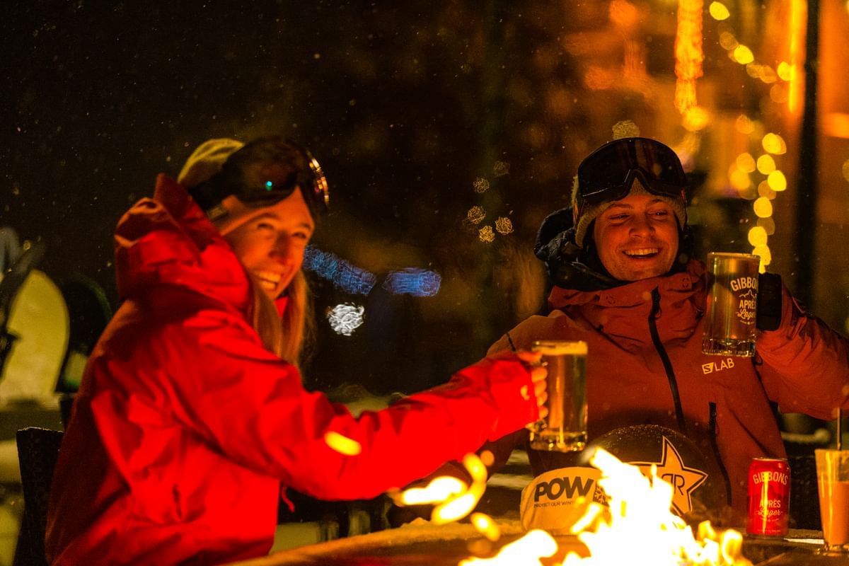 Couple enjoying beer by a campfire near Blackcomb Springs Suites