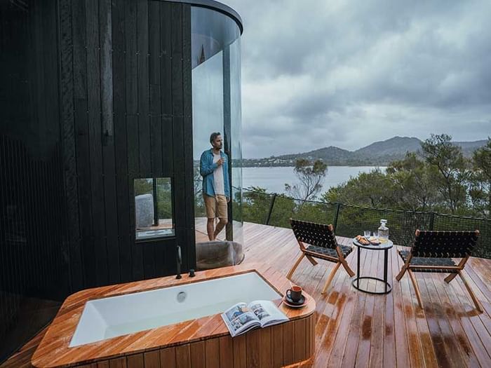 Man overlooking the view from a window while sipping on wine at Freycinet Lodge