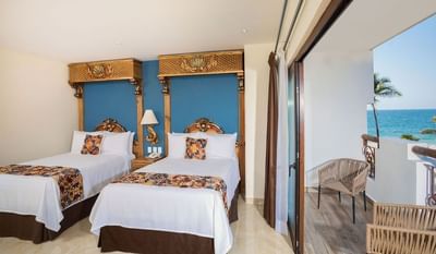 Double bed hotel room with ornate gold headboards and ocean view balcony at Playa Los Arcos Puerto Vallarta 2023