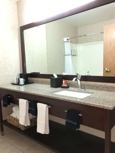 Bathroom with amenities & vanity with large mirror in a room at Boothill Inn & Suites