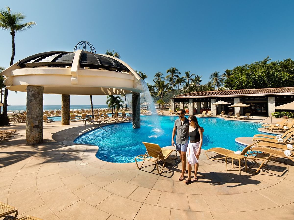 Couple walking by outdoor pool at Pierre Mundo Imperial