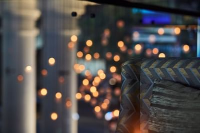 Close-up of a patterned chair with a blurred background of glowing lights in the 2 Lam Son Bar at Park Hyatt Saigon
