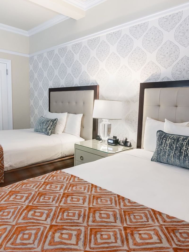 Two queen beds with white linens and decorative pillows with table lamp in Premier Room 2 Double beds at Warwick New York