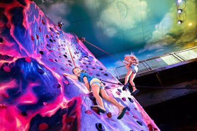 Children enjoying the vibrant indoor rock climbing wall i with safety harnesses in at Margaritaville Resort Biloxi