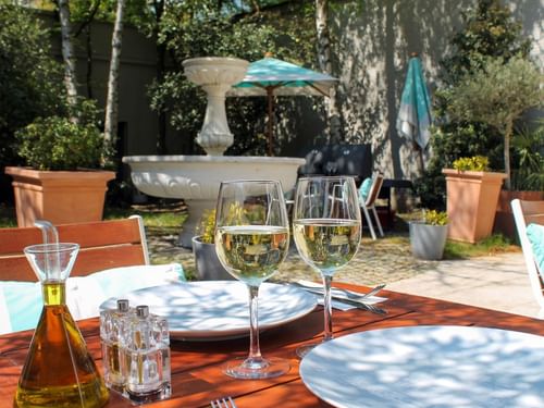 White wine glasses on a sunlit terrace table by the fountain at Hotel Barsey by Warwick