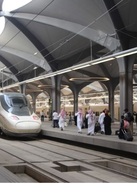 Haramain Railway Station with arched ceilings, a sleek train, and people walking with luggage near Warwick Hotel Jeddah