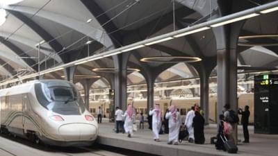 La gare de Haramain, avec ses plafonds voûtés, un train aux lignes épurées et des passants chargés de bagages près de l'hôtel Warwick à Djeddah