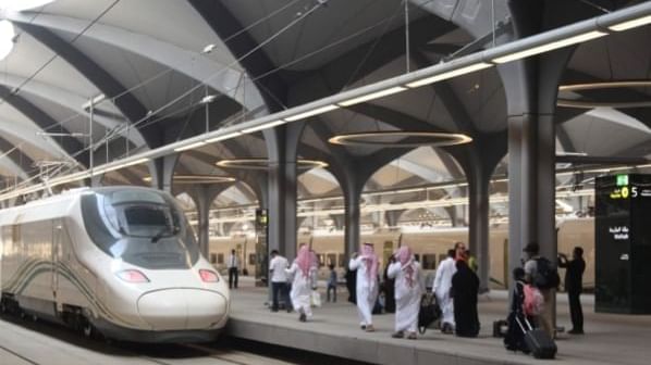Haramain Railway Station with arched ceilings, a sleek train, and people walking with luggage near Warwick Hotel Jeddah