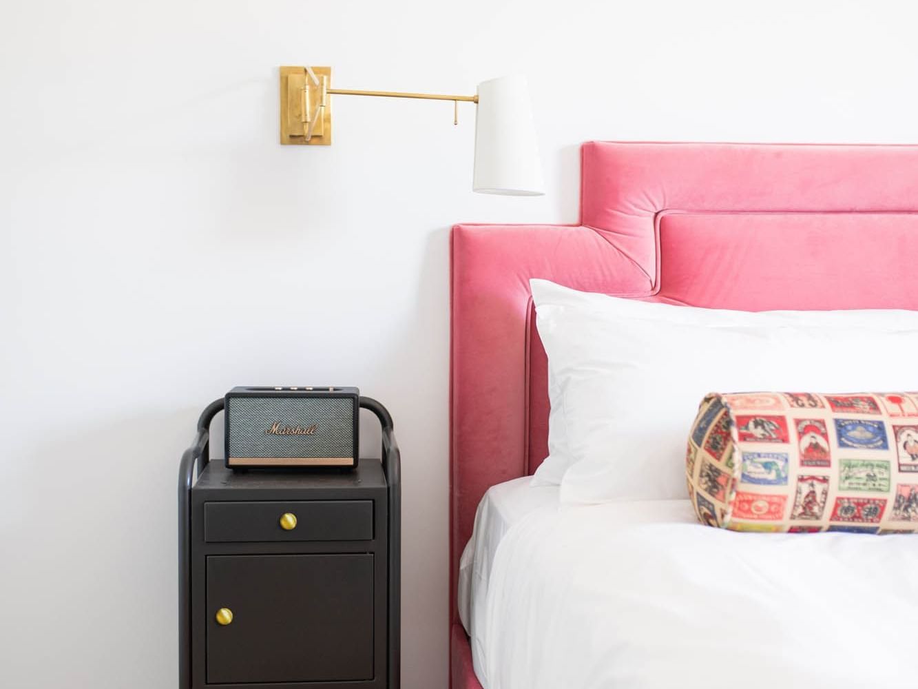 bed with pink headboard in white room