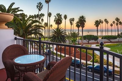 Balcony view from Parkside Partial Ocean View King, with wicker chairs overlooking the Santa Barbara Inn parking and beach
