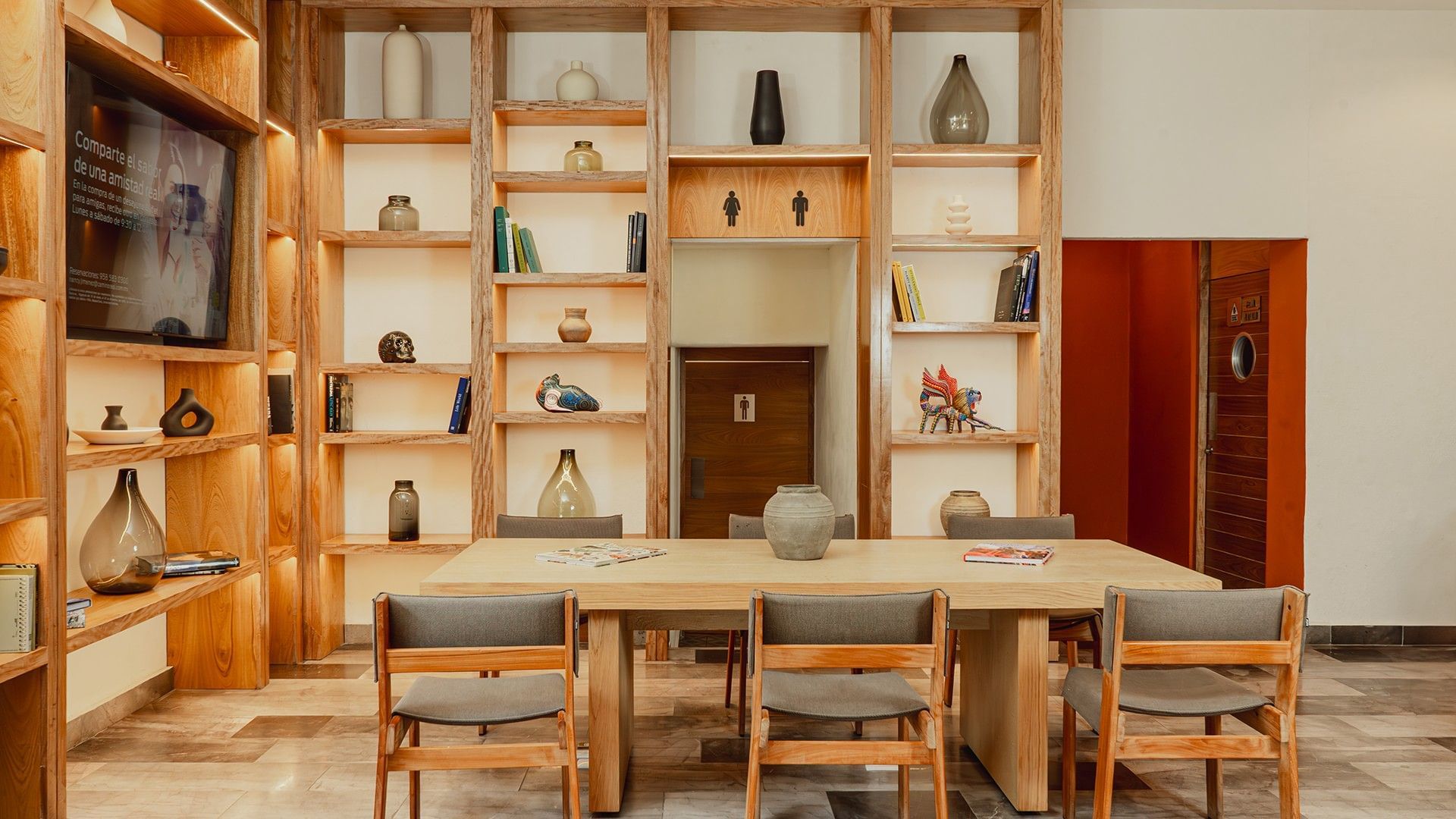 Dining table with cozy chairs and backlit shelves in Library Café & Deli at Camino Real Zaashila Huatulco