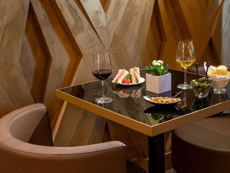 A table arranged with red and white wine, club sandwiches and savory treats in The Lounge Bar at The Style