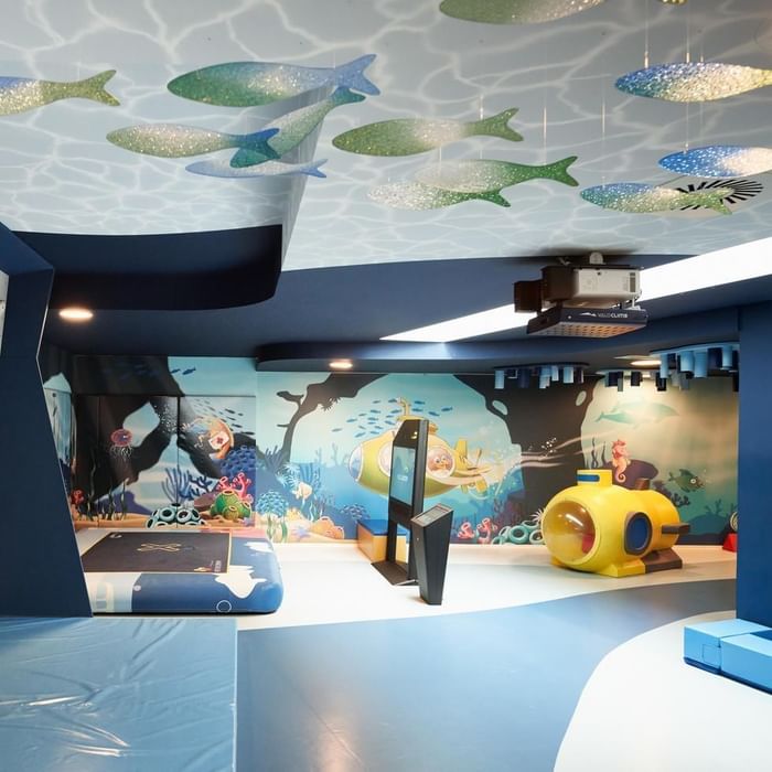 Ein Spielzimmer mit einem Unterwasserthema, bunten Fischen an der Decke und einem gelben U-Boot.