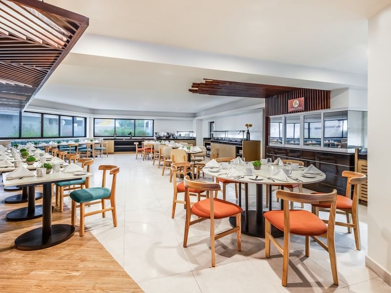 Chulavista restaurant featuring wooden accents, set tables with white linens, and an omelet station bar at Sunvivia Mazatlán