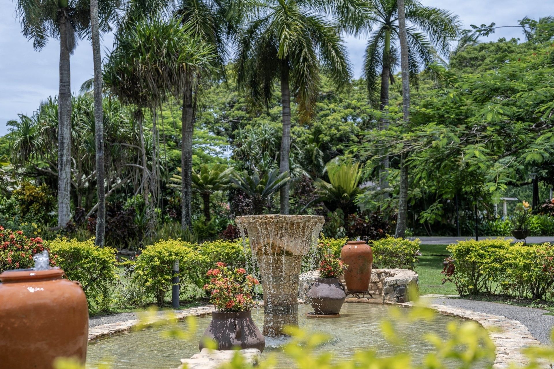 Entrance with Water fountain by clay pots under tall palm trees near a lush tropical garden at The Naviti Resort - Fiji