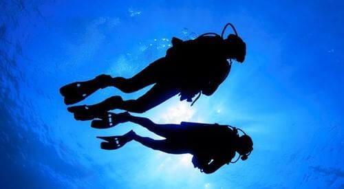 Two scuba divers in the ocean with sunlight near Grand Park Kodhipparu, Maldives