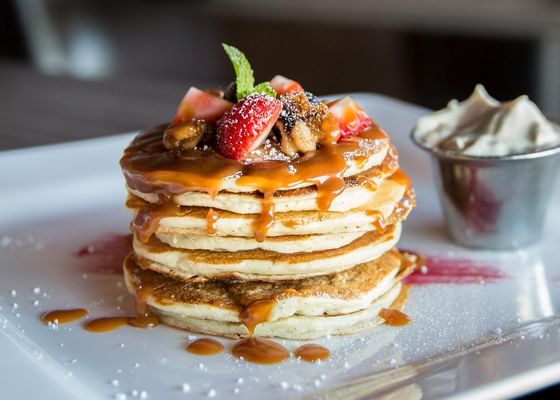 Pancakes topped with honey, berries & served with a cup of whipped cream at Meadowmere Resort