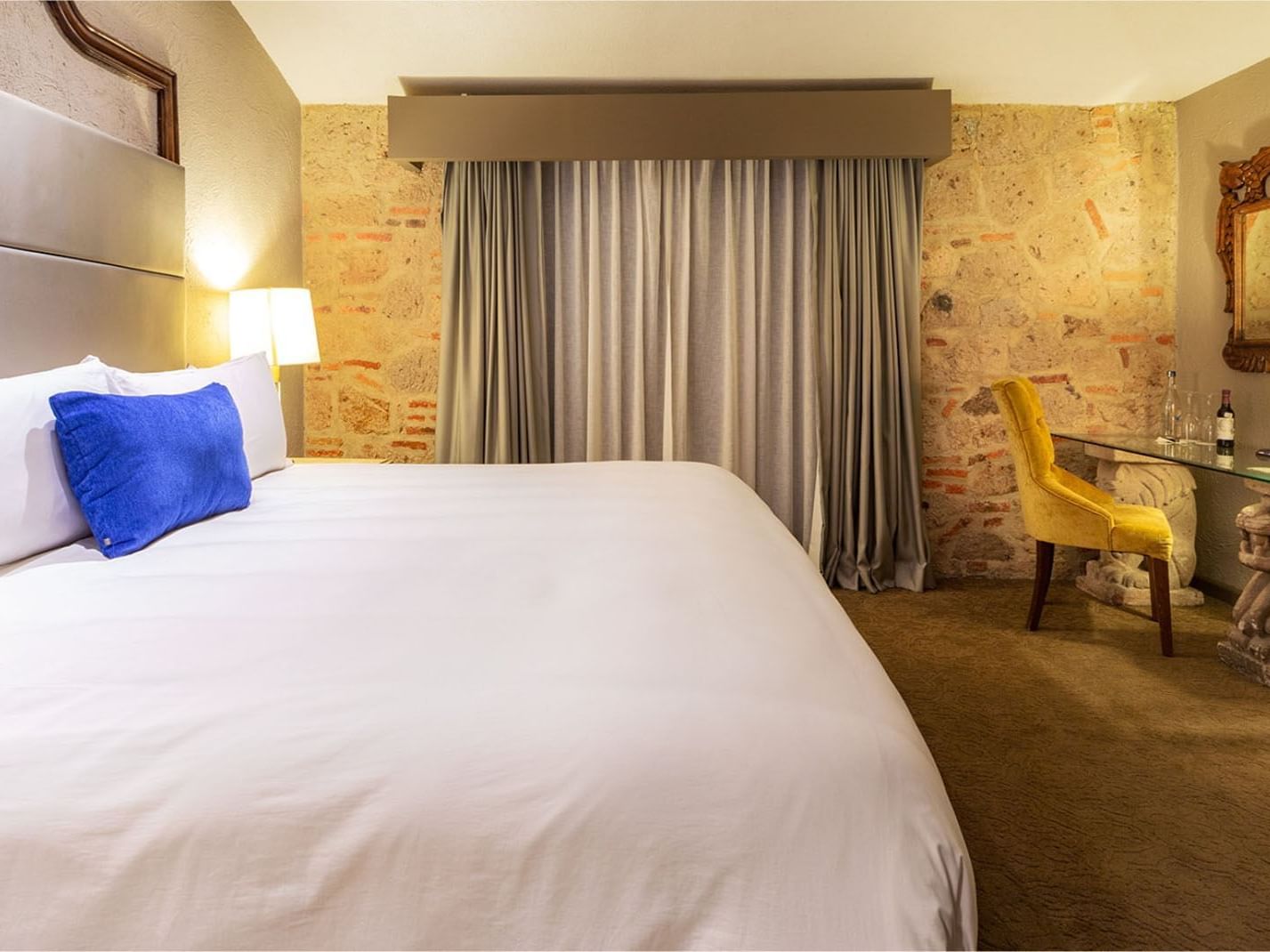 King Master Suite with a blue accent pillow and a stone feature wall, at the iconic Quinta Real Guadalajara
