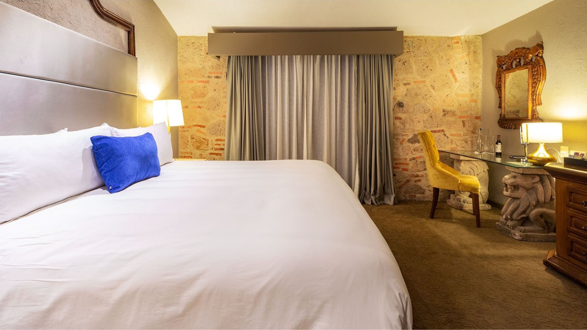 King Master Suite with a blue accent pillow and a stone feature wall, at the iconic Quinta Real Guadalajara