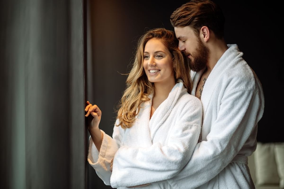 couple in robes looking out of hotel window