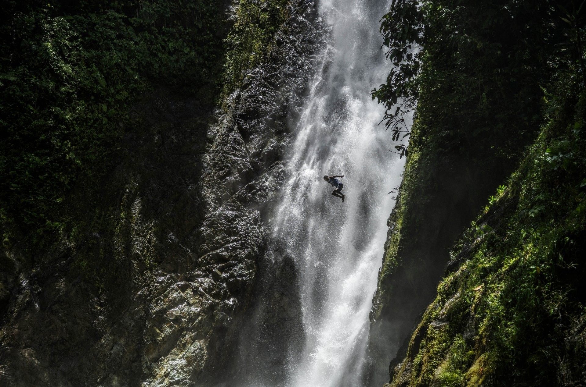 Person leaping into a misty waterfall under tall rocky cliffs near Warwick Fiji Resort and Spa